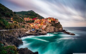 Un pueblo costero con edificios coloridos, asentado en un acantilado con vistas a aguas turquesas.