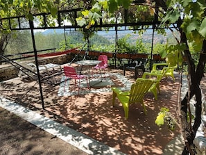 A covered outdoor seating area with chairs and tables, surrounded by a pergola with vines. - Belle Èpoque - La Villa Imperiale (Carrara)