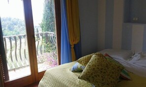Un dormitorio con cama, ventana con cortinas y vistas a un balcón.