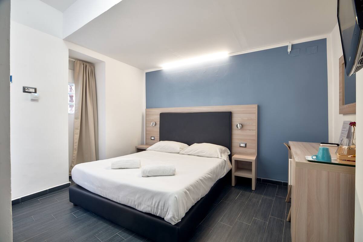 Una habitación de hotel moderna con una cama grande, mesitas de noche, un escritorio y un televisor de pantalla plana.