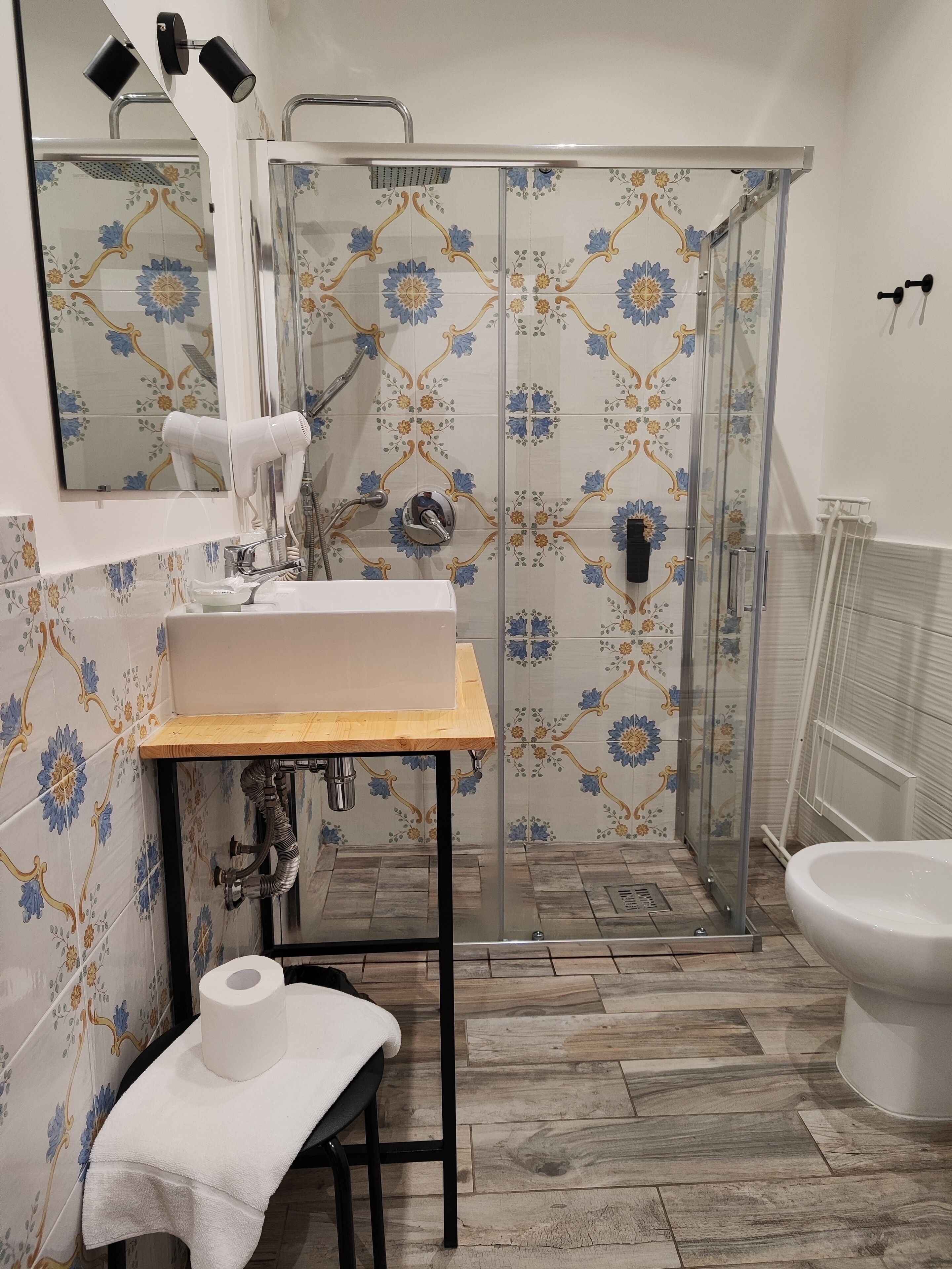 A bathroom with a shower, toilet, sink, and a mirror.