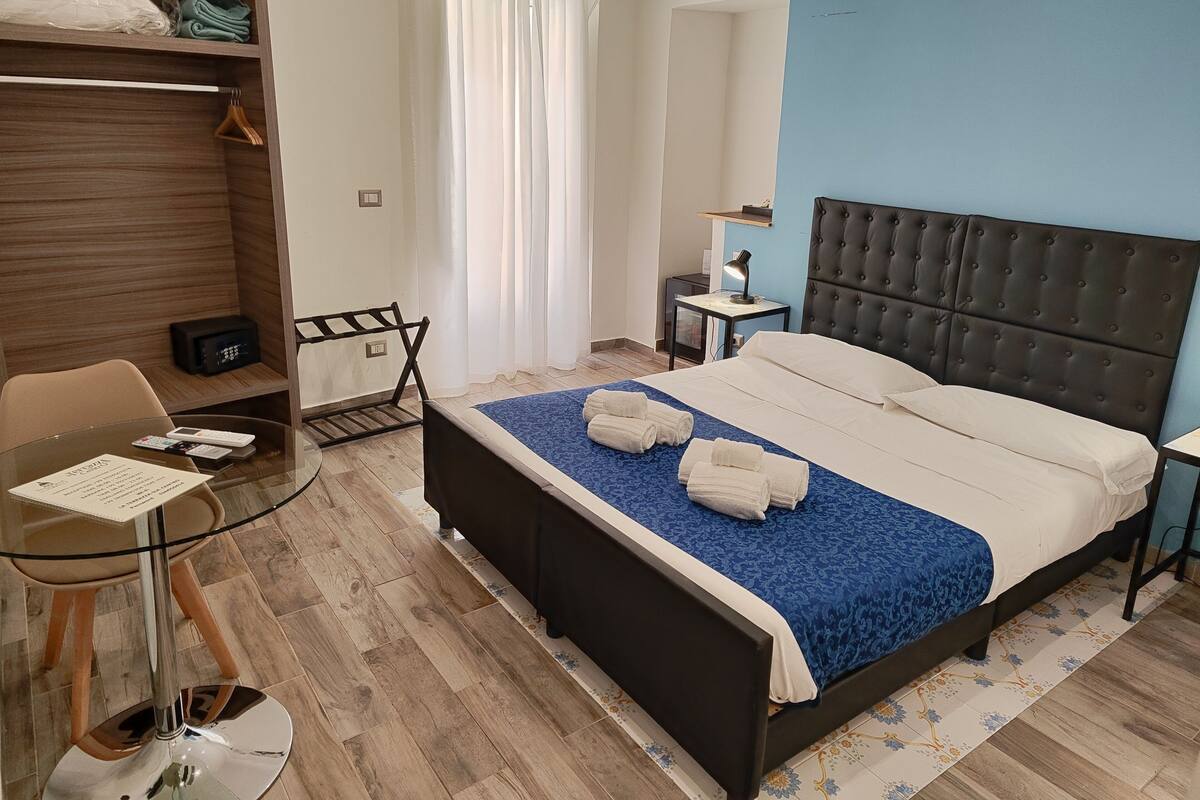Una habitación de hotel ordenada con cama, escritorio, silla y armario.