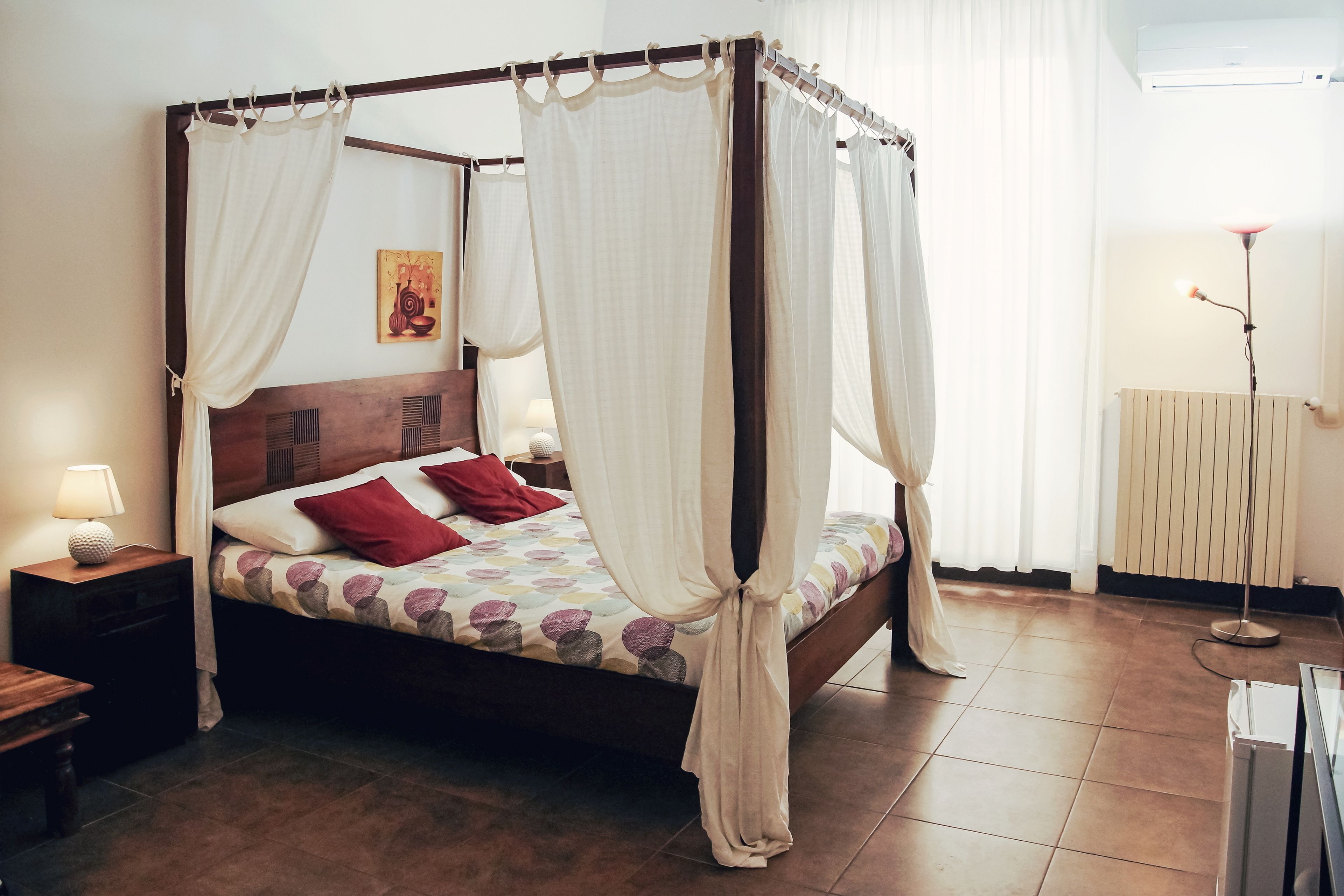 Un lit à baldaquin, une table de chevet avec une lampe et un radiateur dans la pièce.