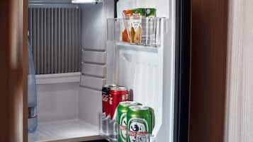 Et køleskab med en vandflaske, to dåser Coca-Cola og tre dåser Best øl.