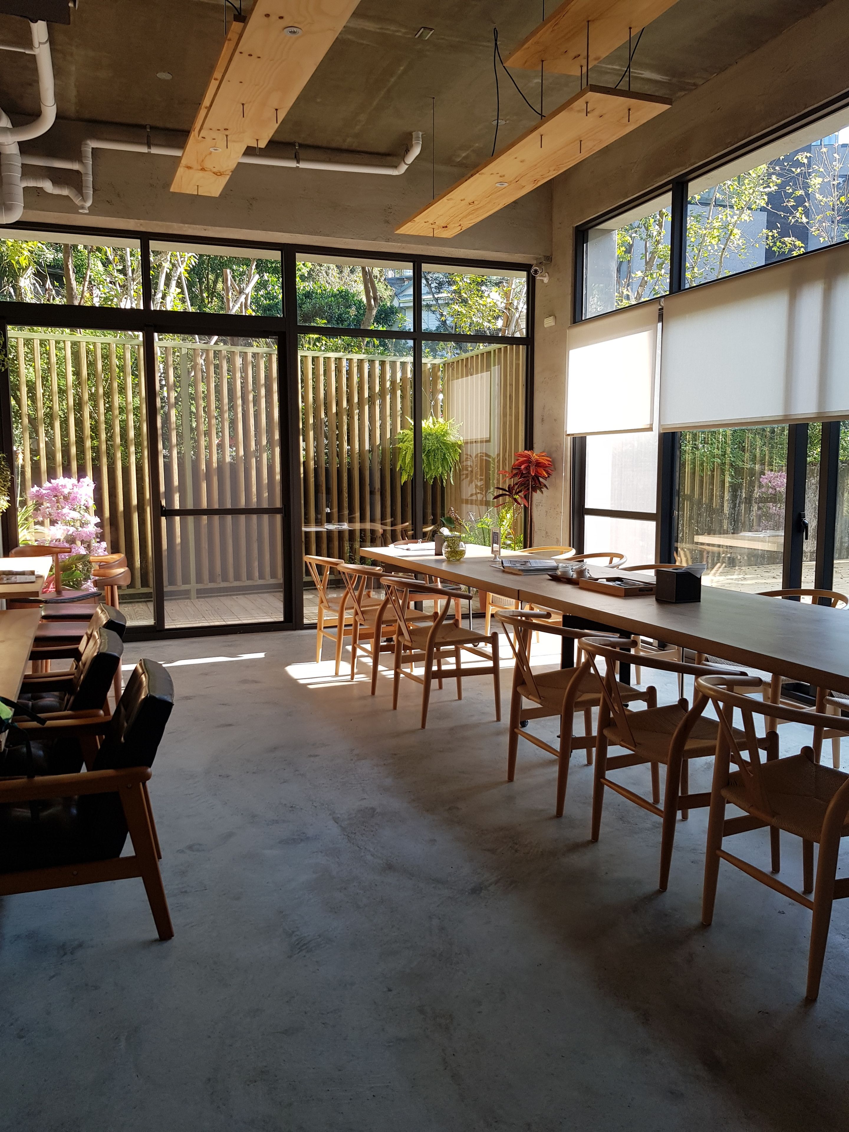 A spacious dining area with large windows, wooden tables, and chairs.