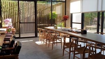 A spacious dining area with large windows, wooden tables, and chairs.