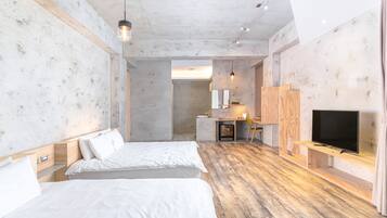 A modern hotel room with two beds, a wooden floor, a TV, and a small desk area.