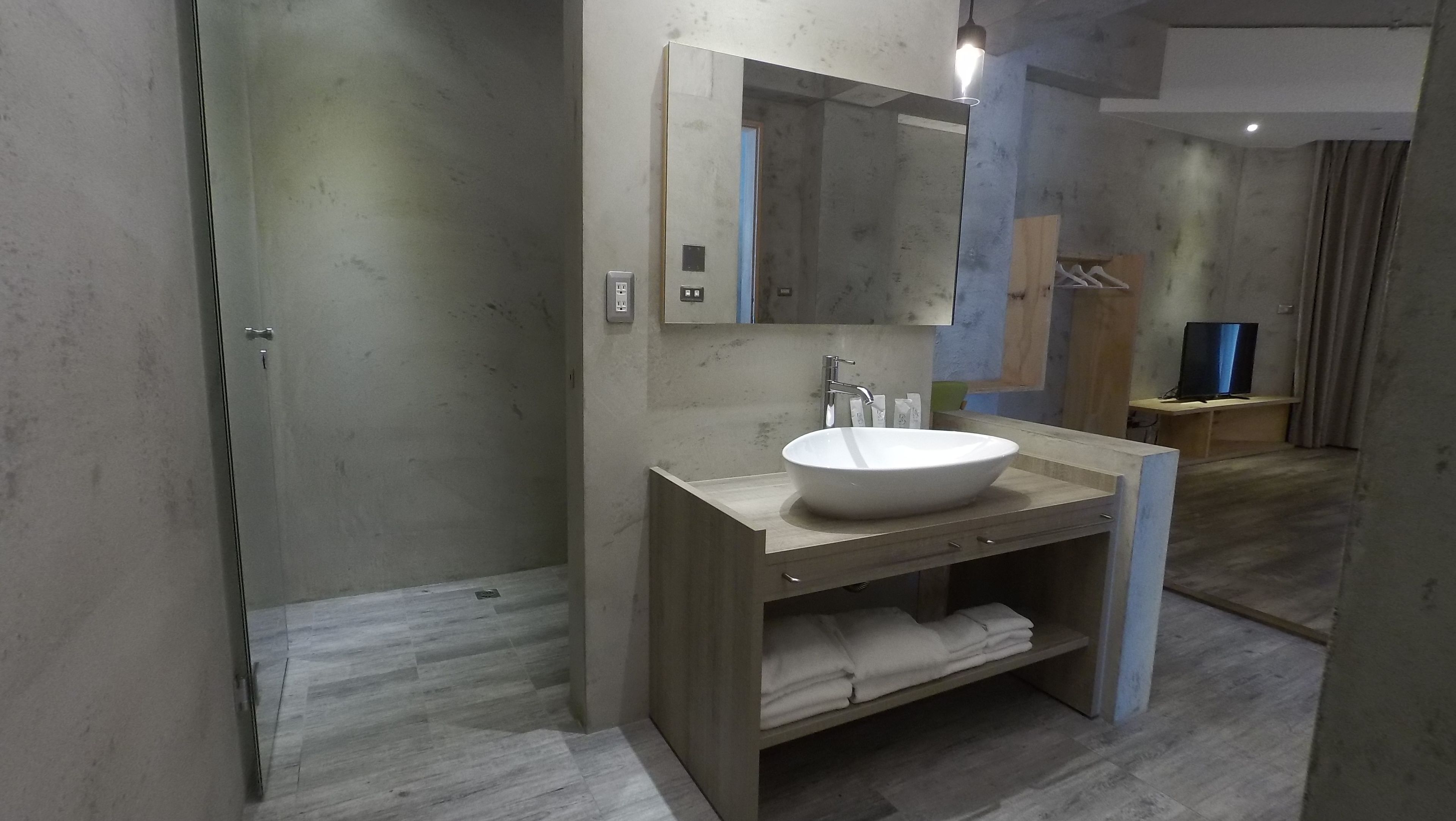 A modern bathroom with a large mirror, a white sink, and a wooden vanity.