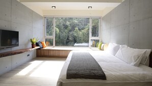 A modern bedroom with a large bed, a built-in bench with a TV, and a window overlooking greenery. - Sun Moon Inn (Yuchi)