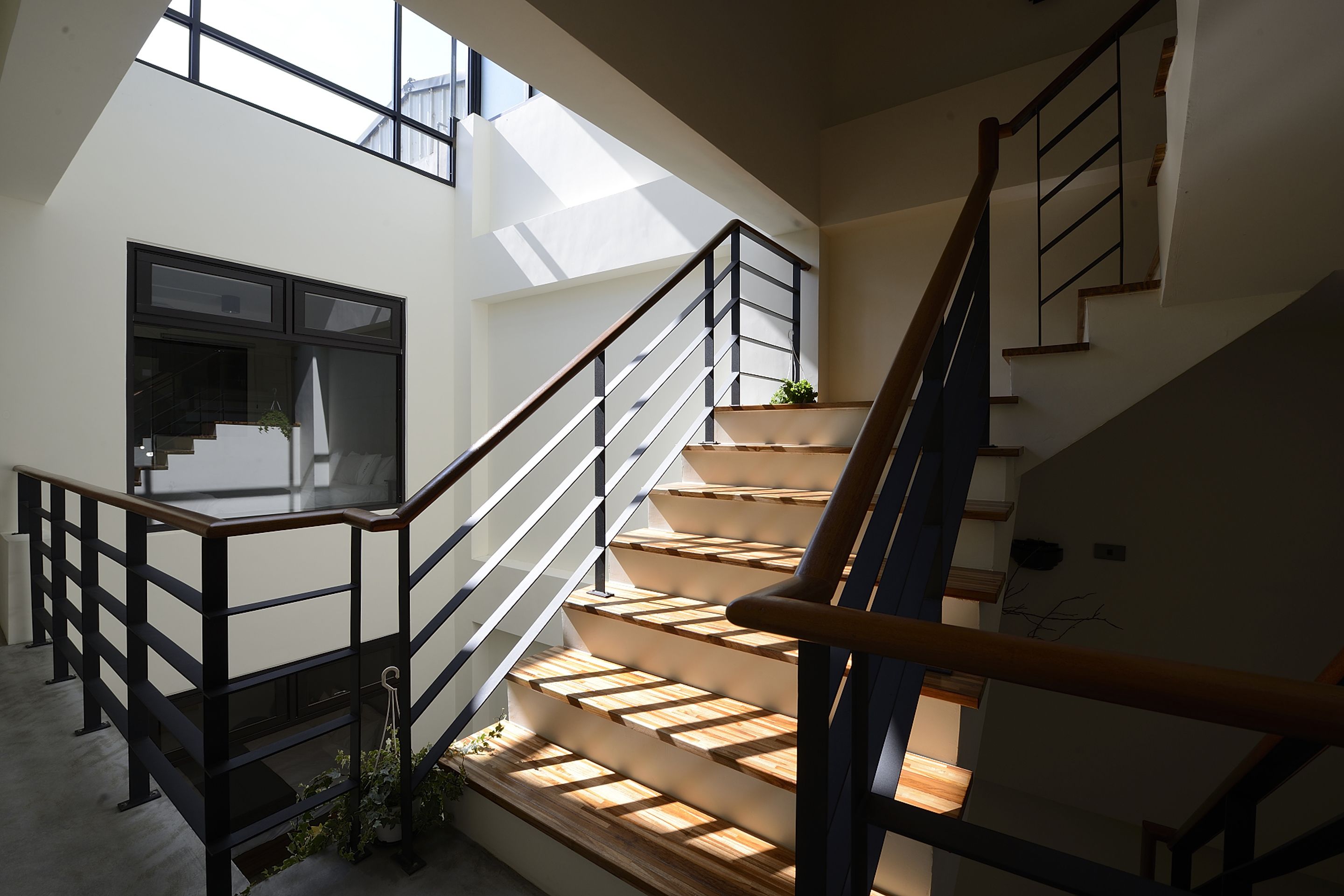 Un interior moderno con una escalera, barandillas de vidrio y vistas al exterior.