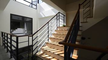 Un interior moderno con una escalera, barandillas de vidrio y vistas al exterior.