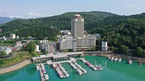 A coastal marina with multiple boats docked, a prominent hotel building, and a mountainous backdrop. - Sun Moon Inn (Yuchi)