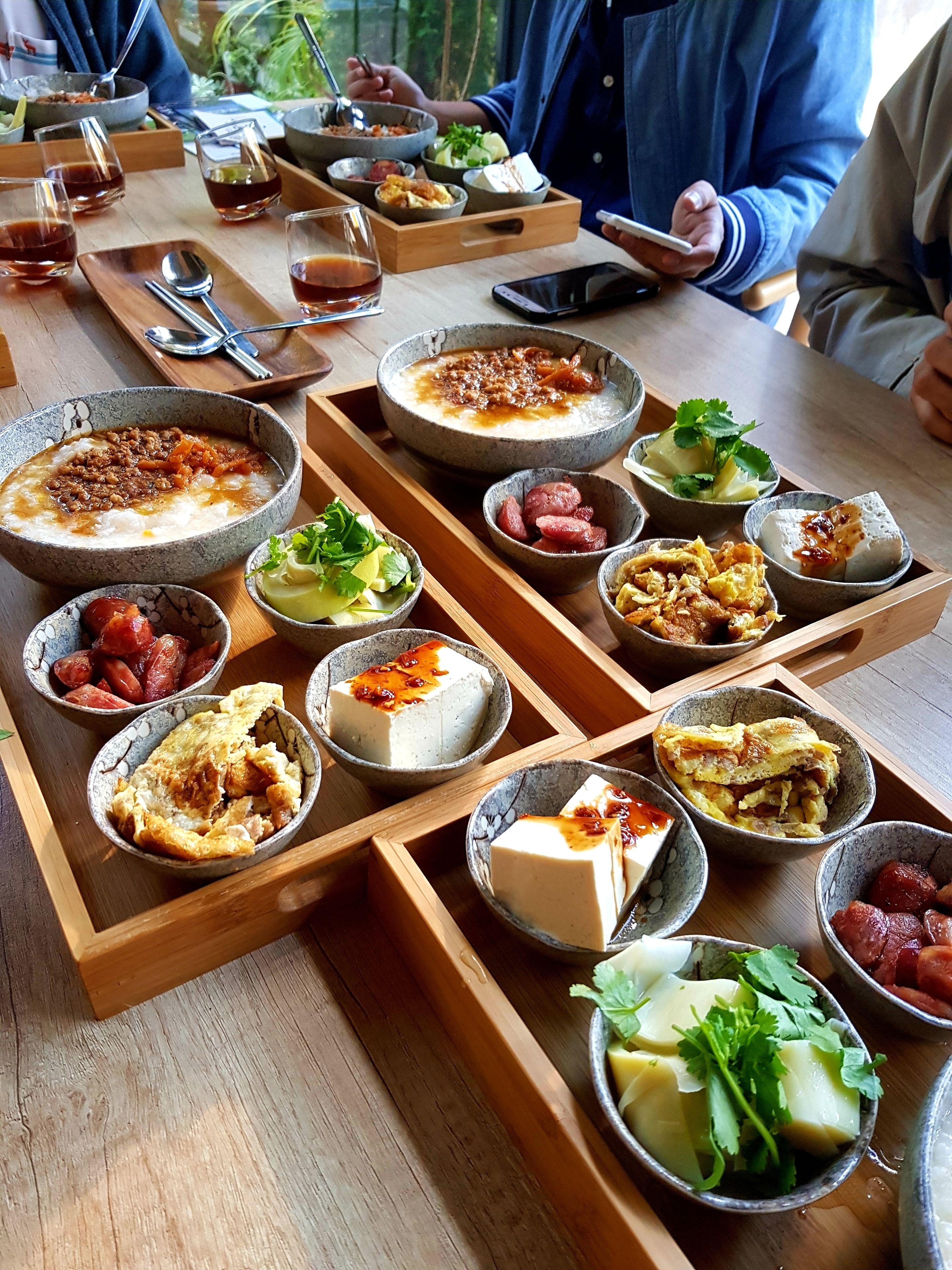 Una mesa de madera con diversos platos y bebidas, probablemente en un restaurante o cafetería.