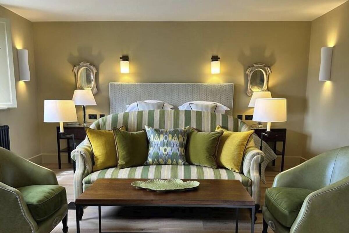 Una habitación con un sofá a rayas, dos lámparas, un espejo y una mesa de centro de madera.