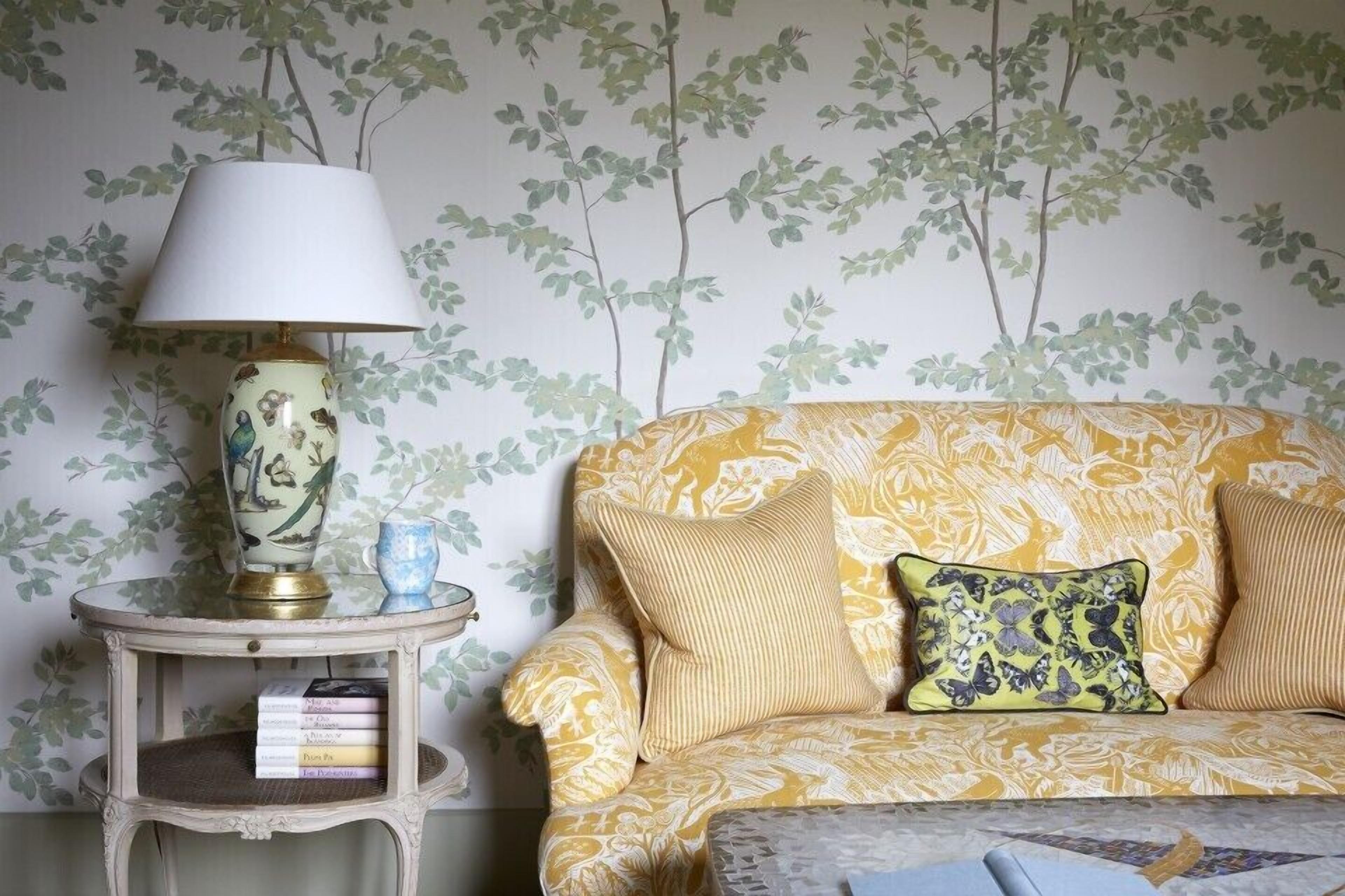 A room with a patterned sofa, a small side table with a lamp, and a bookshelf.