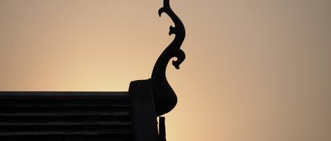 A silhouette of a building's roofline against a sunset sky.