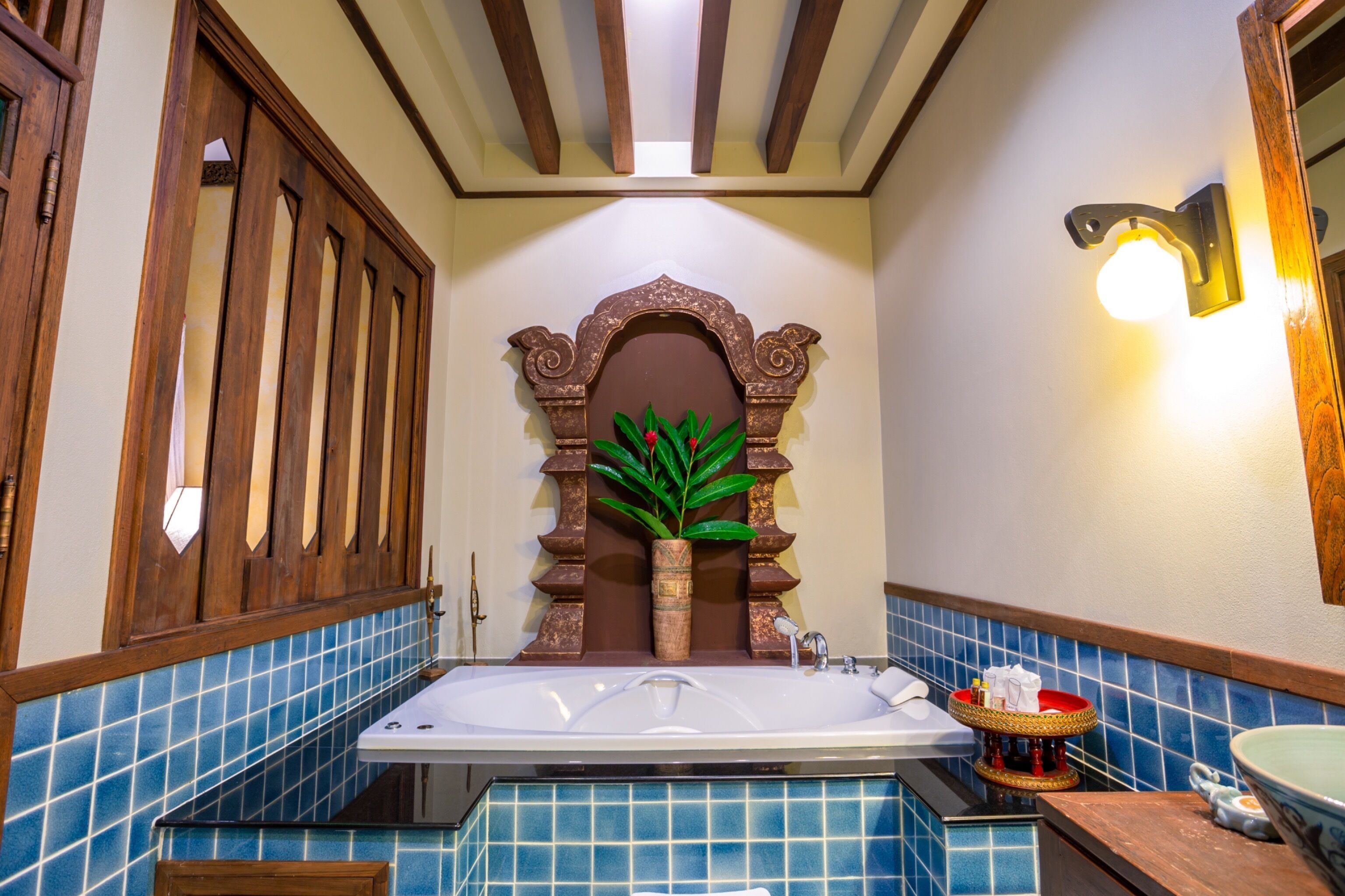 Un baño con una bañera grande, paredes de azulejos azules y una puerta de madera.