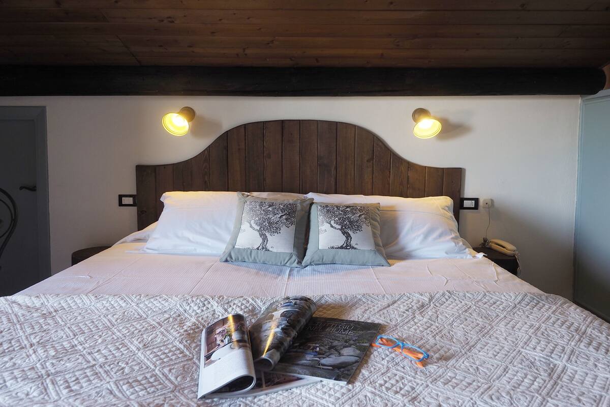 A neatly made bed with a quilt, two pillows with tree designs, and a magazine on the bed.