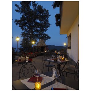 Un espacio de comedor al aire libre con mesas dispuestas para dos, con copas de vino y velas.