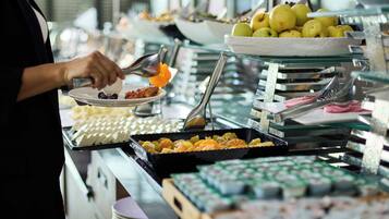 Un bufé con diferentes opciones de comida y una persona servándose.