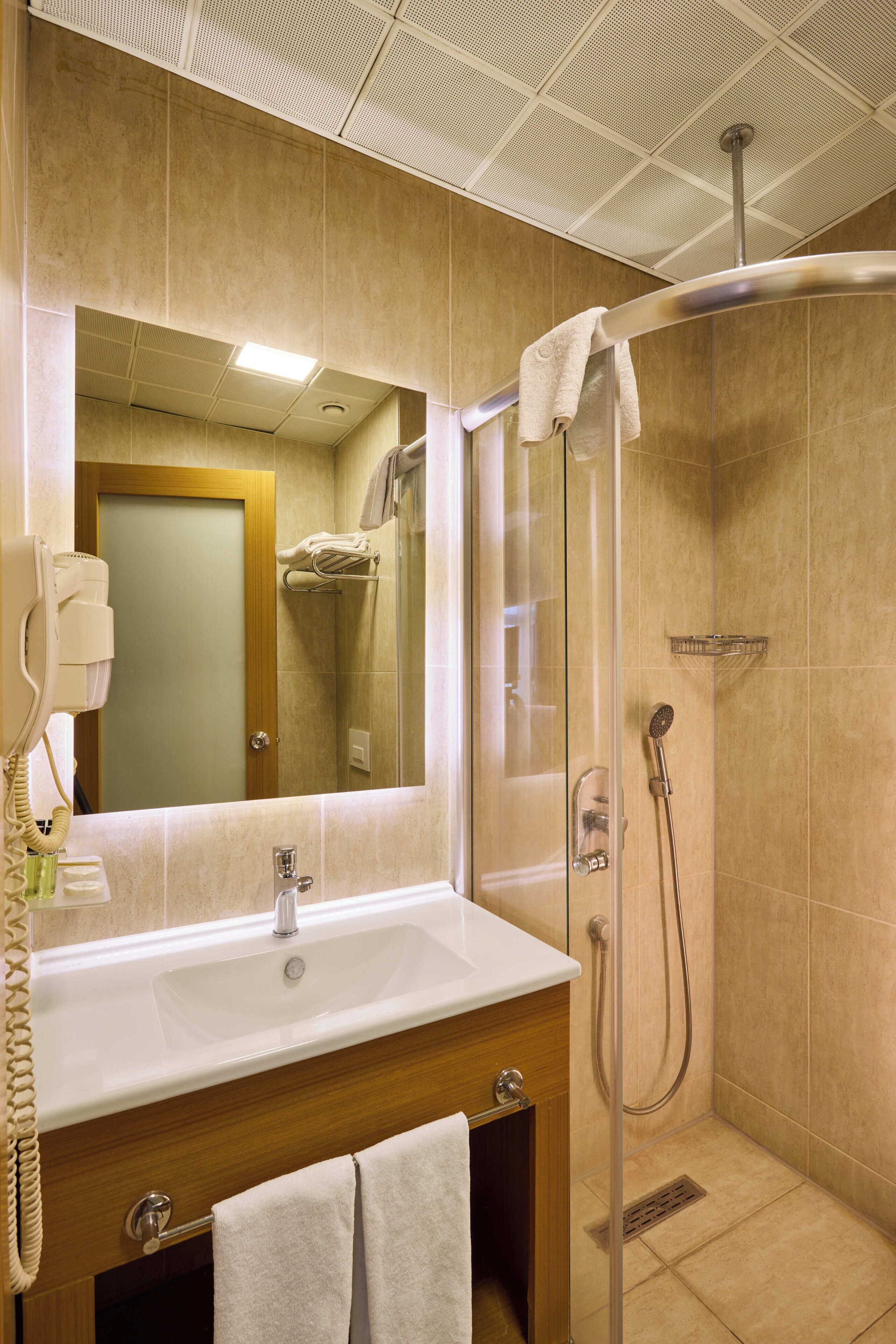 Un baño con lavamanos, espejo y ducha.