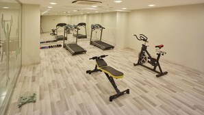 Un gimnasio con cintas de correr, elíptica, bicicleta estática y pesas libres.
