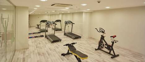 A gym with treadmills, an elliptical, a stationary bike, and free weights.