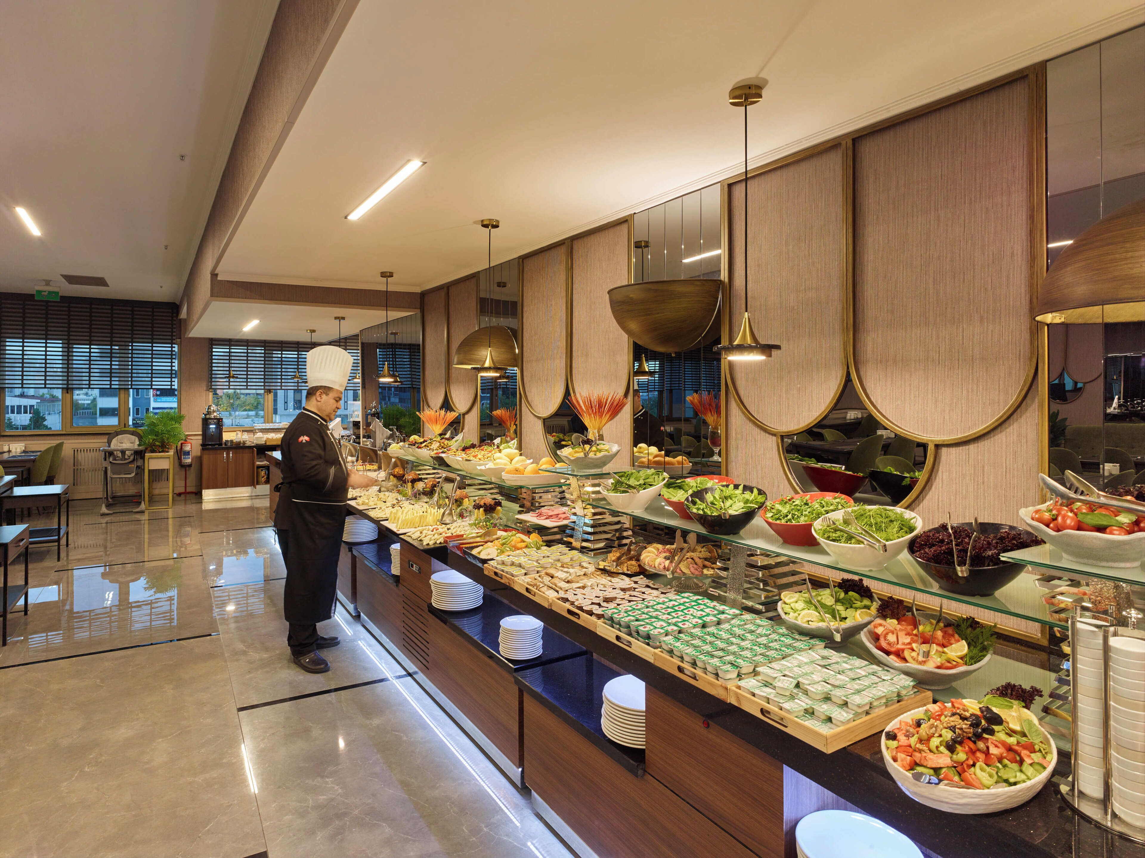 Buffet-pöytä, jossa on monipuolinen valikoima ruokia, sekä tarjoilija.