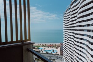 A high-rise hotel with a view of the ocean and a pool area.