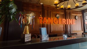 Un mostrador de recepción con un trofeo, una planta y un cartel que dice 'TANGERINE'.