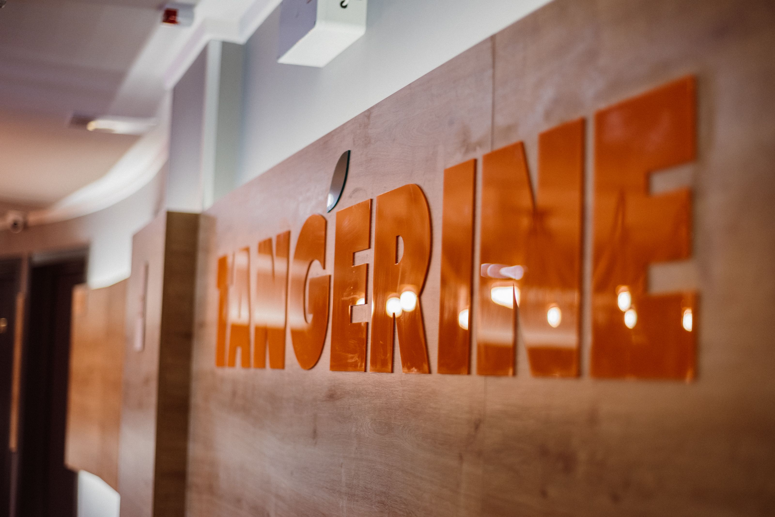 Pared de madera con la palabra "ANGERINE" en letras grandes y reflectantes.