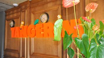 A wooden wall with clocks and a large orange sign reading "TANGERINE."