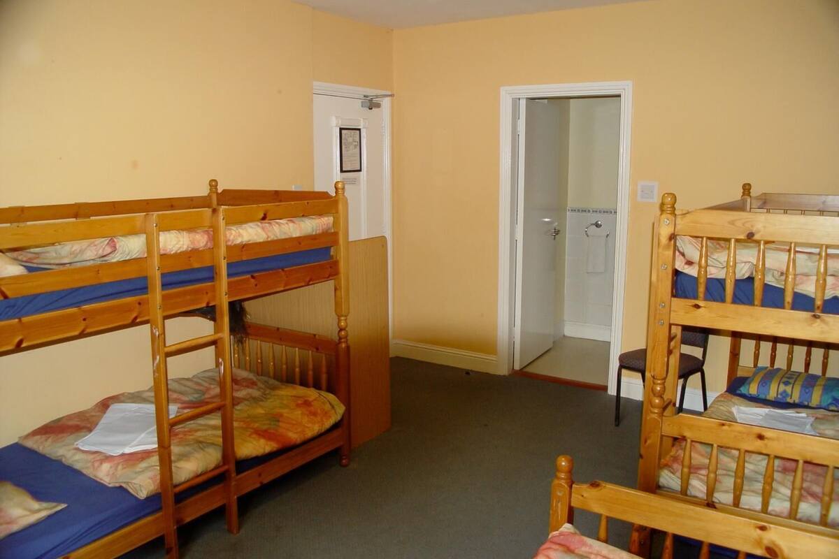 A dormitory room with bunk beds, a door, and a small white cabinet.