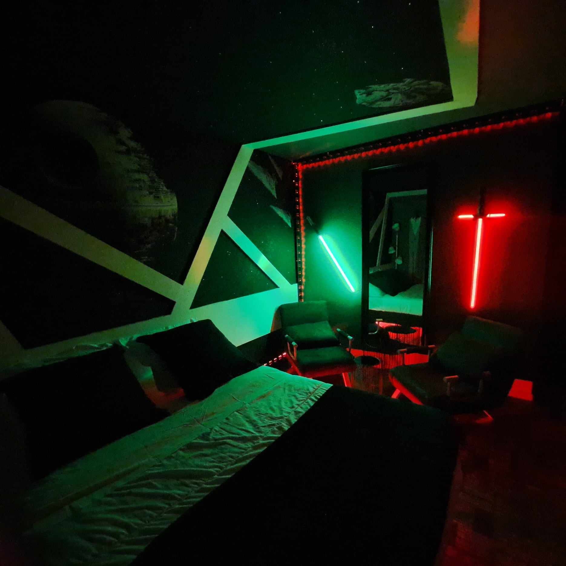 Una habitación tenuemente iluminada con una cama, sillas y un escritorio.