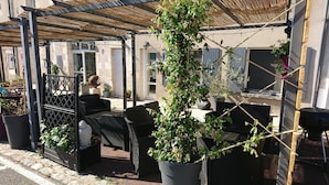 Un patio al aire libre con pérgola, asientos y plantas en macetas.