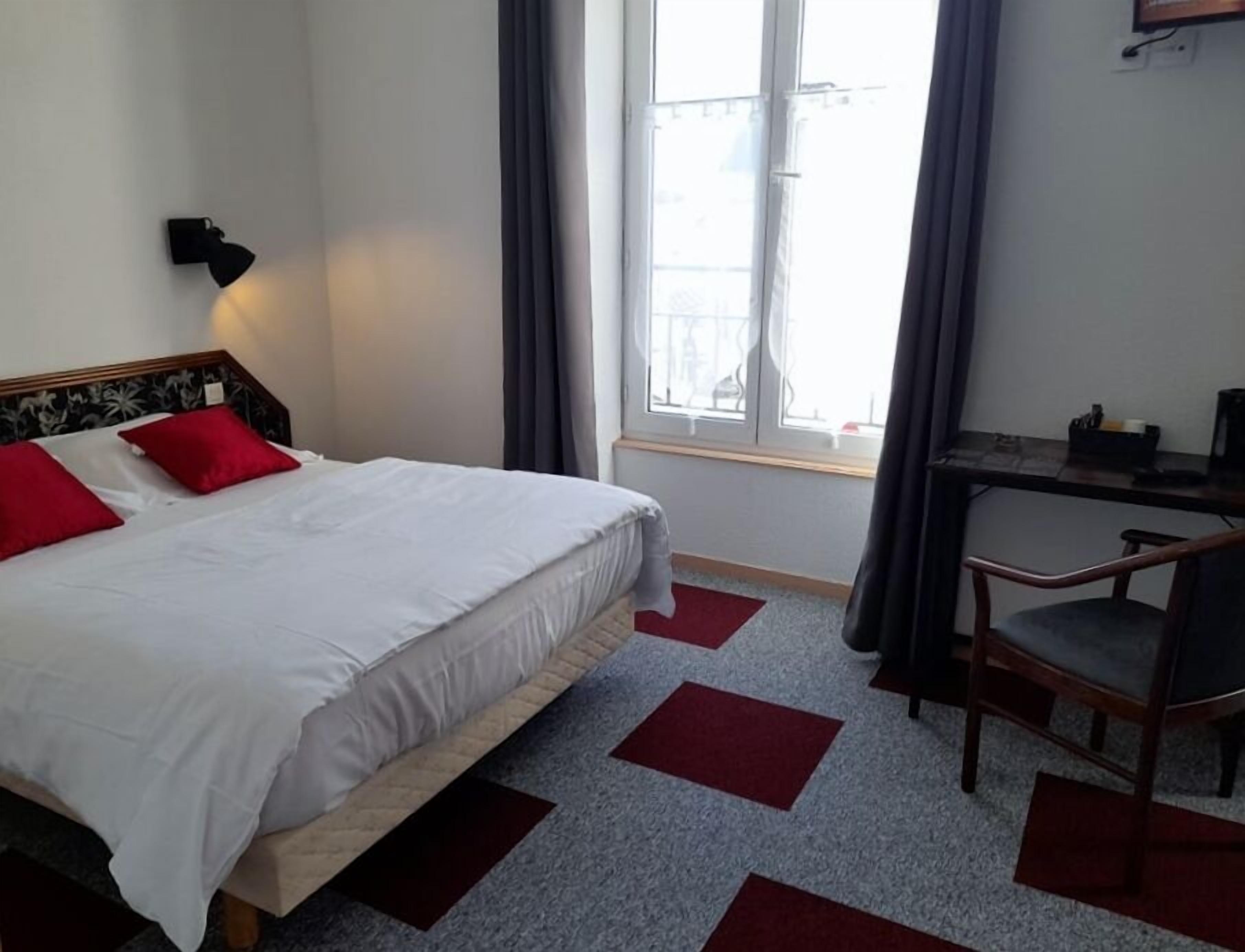Ein Hotelzimmer mit einem großen Bett, einem Schreibtisch und einem Sessel.