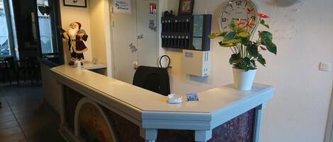 A reception desk with a clock, a potted plant, and a Santa Claus decoration.
