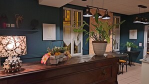 Una zona de recepción con mostrador de madera, plantas en macetas e iluminación colgante.