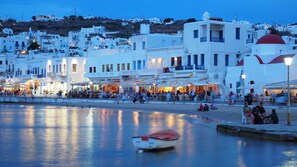 A coastal town with white buildings, a calm sea, and a small boat.