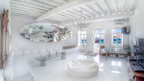 A spacious, modern living room with a large mirror, a glass coffee table, and a white bean bag. - The Loft Mykonos Town (Mykonos)