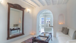 A spacious, well-lit room with a large mirror, a white sofa, a coffee table, and a colorful rug. - The Loft Mykonos Town (Mykonos)