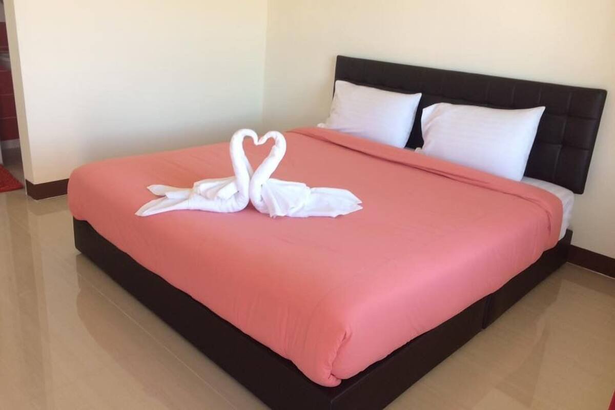 A neatly made bed with a pink bedspread and two white pillows.