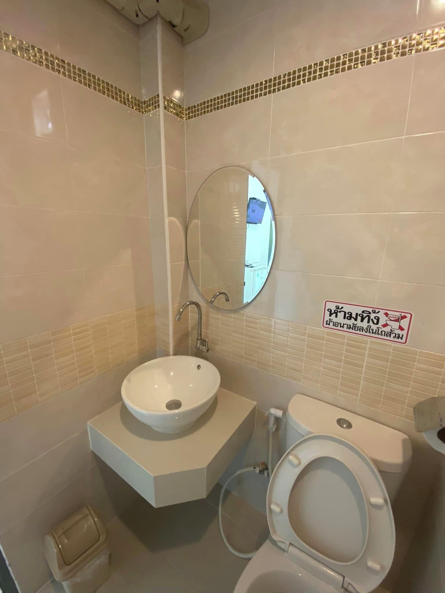 Et badeværelse med en hvid vask, toilet og et spejl.
