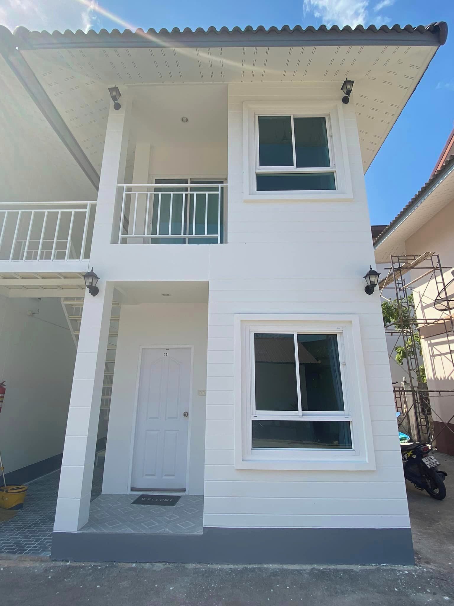 A two-story building with a white exterior, a balcony on the upper floor, and a door marked with the number 11.