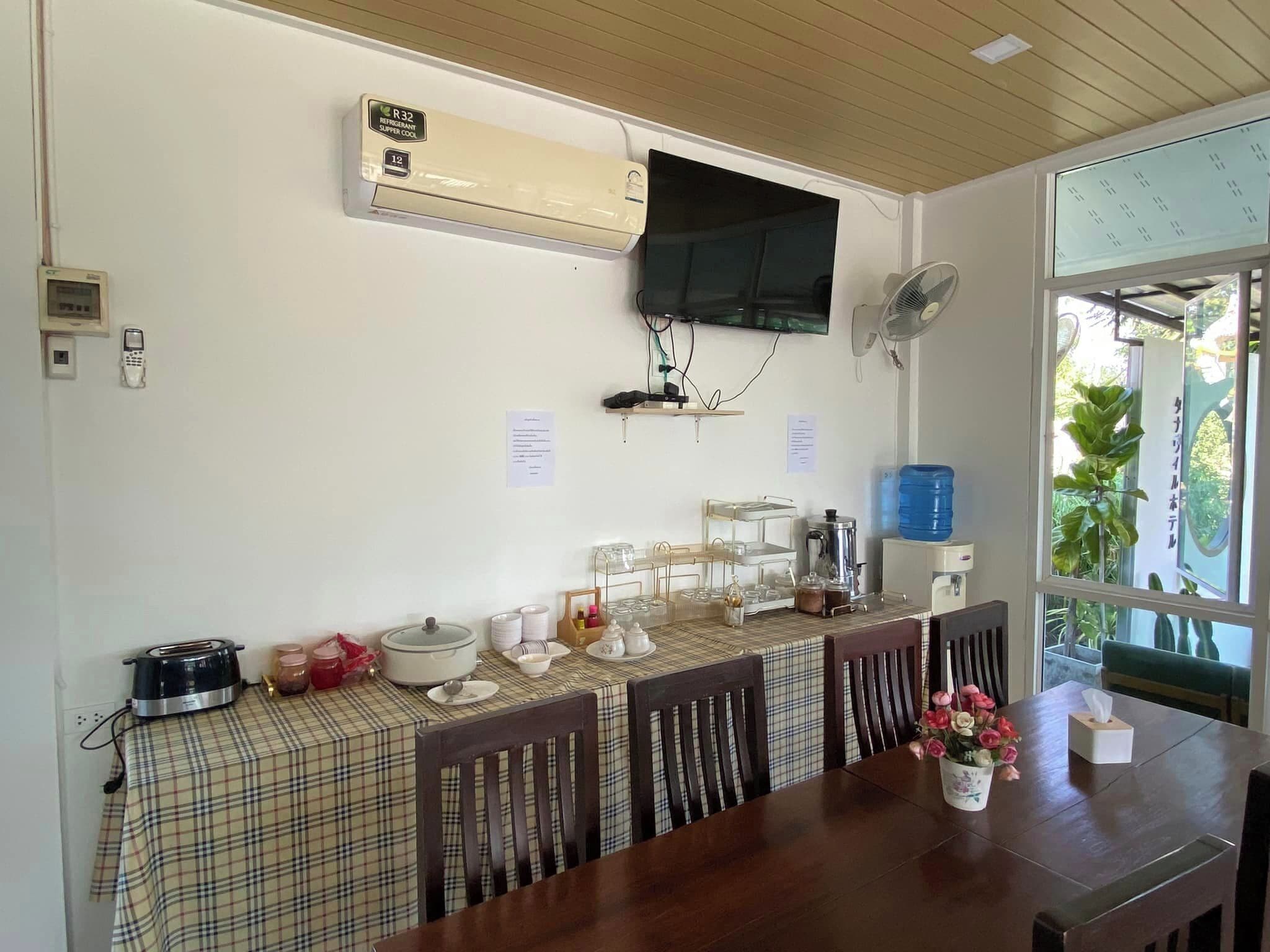 Un comedor con montaje tipo bufé, aire acondicionado instalado en la pared, televisor y dispensador de agua.