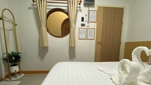 A hotel room with a bed, a round mirror, a door, and a wall-mounted plant. - ThanaVill Resort (Mae Sot)