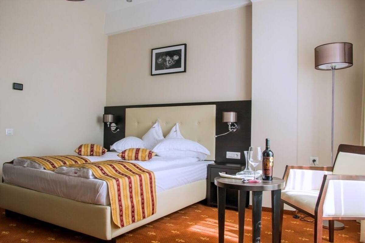 A hotel room with a bed, bedside tables, a chair, a lamp, and a framed picture on the wall.