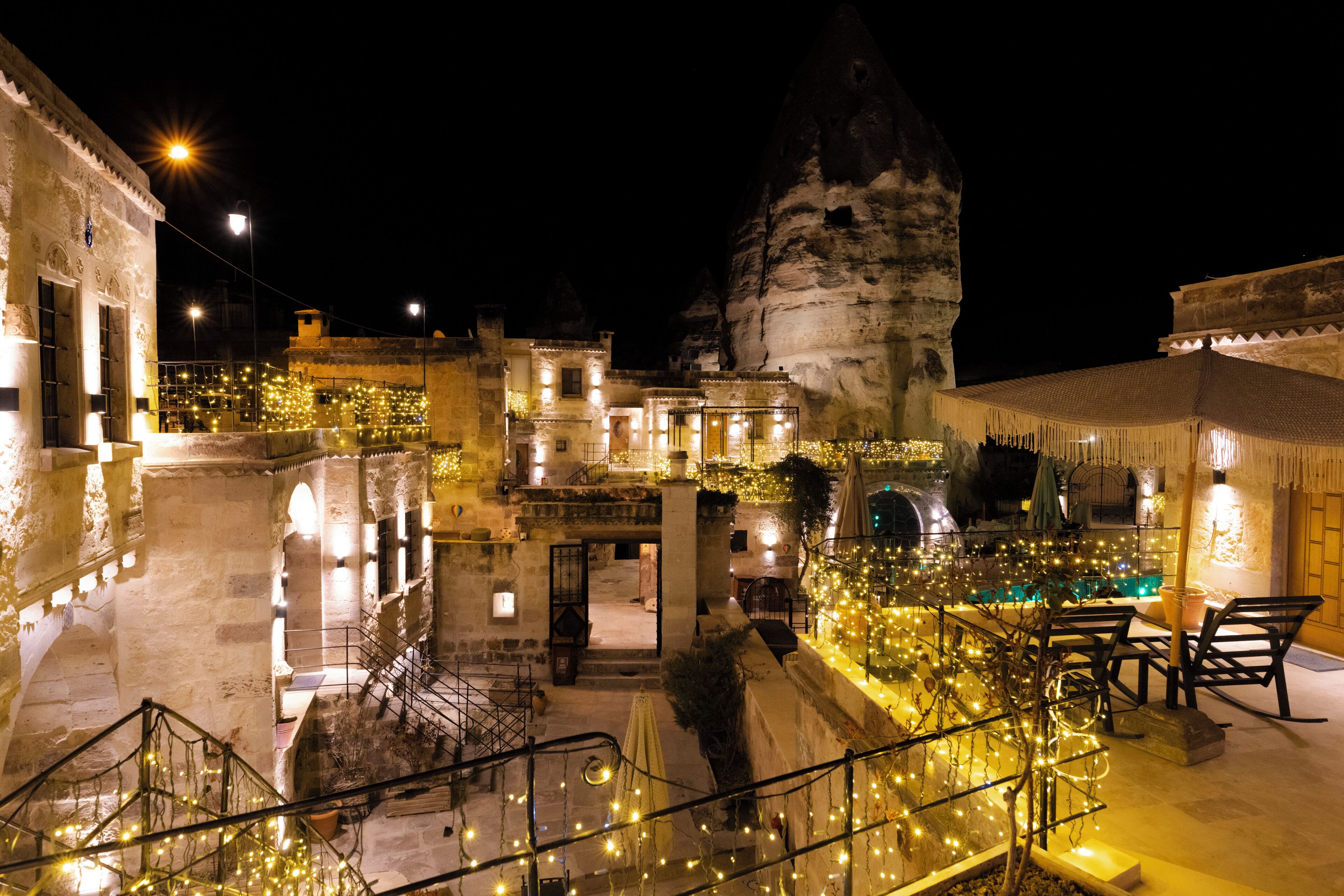 A historic building with stone architecture, outdoor seating, and string lights.