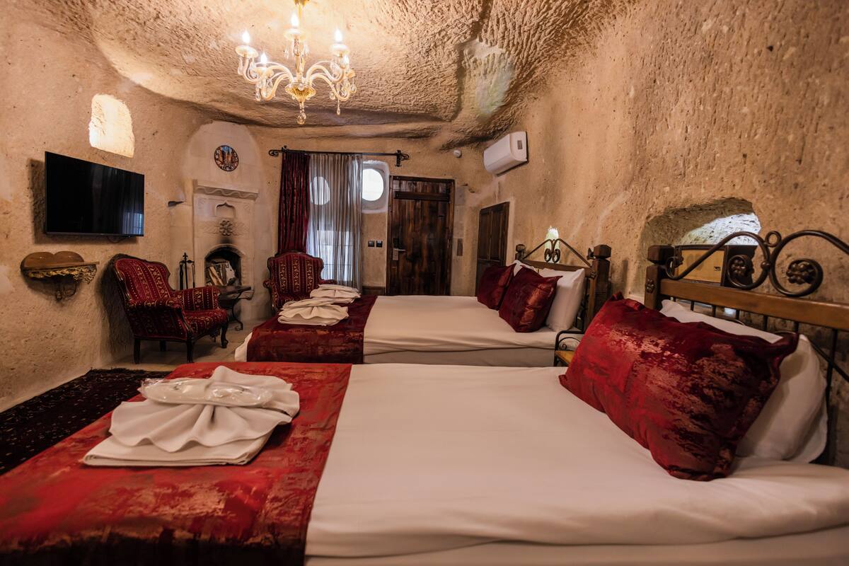 Une chambre d’hôtel avec deux lits, un lustre, un téléviseur à écran plat et une cheminée.