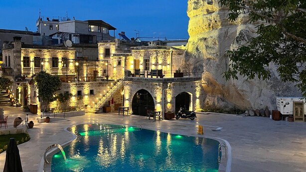 A pool area with a stone building and a large rock formation. - Göreme Cave Suites (Nevsehir)